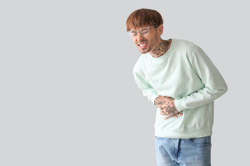 Young man suffering from stomach ache on light background