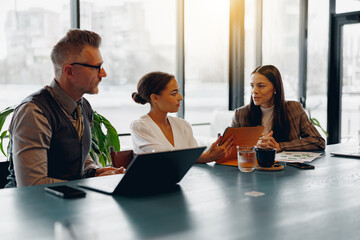 Professionals are actively engaged in collaborative discussions while utilizing technology in a bright office space