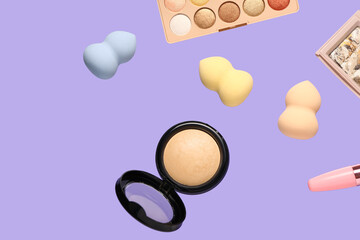 Flying decorative cosmetics on lilac background