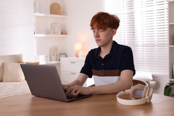 Teen problems. Depressed teenage boy with laptop at desk indoors