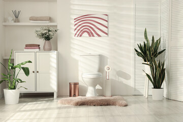 Ceramic toilet bowl, houseplants and necessities in restroom