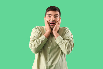 Afraid young man on green background