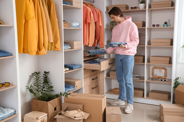 Handsome young man with wardrobe boxes arranging stylish jeans in dressing room