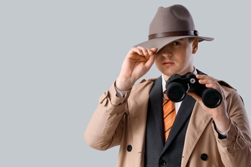 Male spy with binoculars on light background, closeup