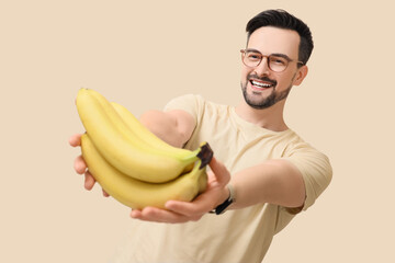 Young man with bananas on beige background