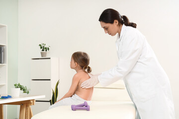 Female osteopath and little patient on couch in clinic