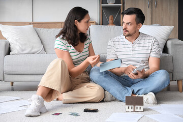 Young man doing calculation while his wife sitting with empty wallet at home. Bankruptcy concept