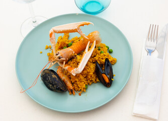 Portion of Spanish seafood paella with lobster, mussels, calamari and shrimps on plate