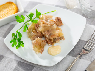 Traditional dish of Russian cuisine is a kholodets made from a jelly-like mass from cooling meat broth with pieces of meat. ..Served with sauce and garnished with a sprig of fresh parsley