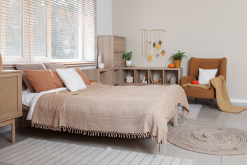 Interior of stylish bedroom with pumpkins and autumn decor on shelving unit near window