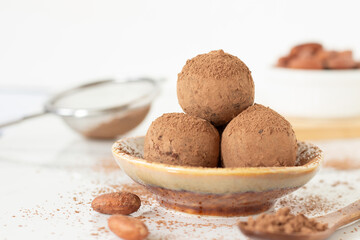 Chocolate truffles with cocoa powder on white kitchen table with copy space. Close-up. Healthy homemade raw dessert or snack.