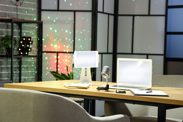 Naklejka premium Podcaster's workplace with laptop, tablet computer and microphone in studio at night