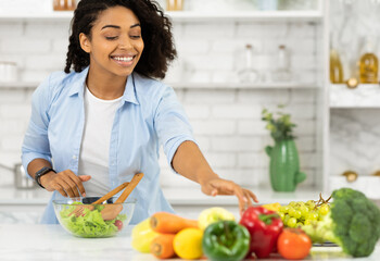 Casual black girl preparing healthy lunch for her family in modern kitchen, taking vegetables, copyspace