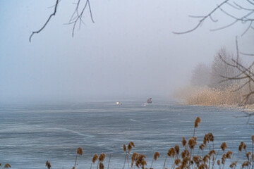 Naklejka premium The image shows a fisherman on the ice in thick fog. The fog obscures the surroundings, creating a mysterious atmosphere.