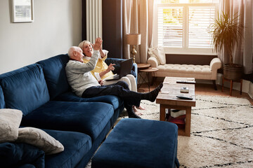 High five, laptop and retirement with a senior couple on a sofa in the living room of their home...