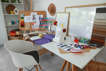 Fashion designer's workplace with sewing machine and thread spools in studio