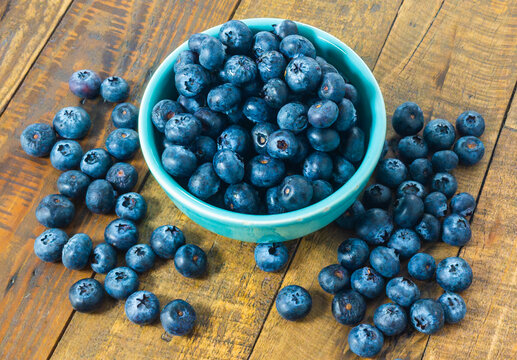 Closeup of blue berries in a bowl and on a table.