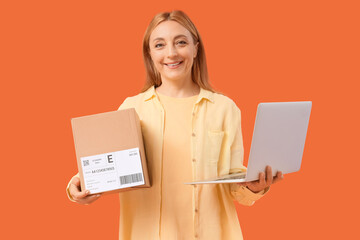 Female online store seller with parcel and laptop on orange background