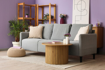 Comfy sofa, coffee table and shelving unit in beautiful interior of living room