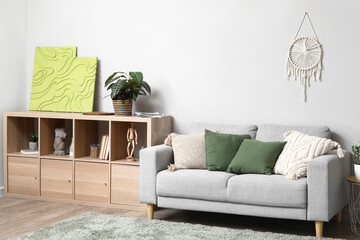 Cozy sofa and sideboard with houseplant and pictures in room