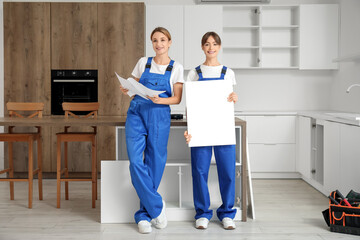 Female workers with furniture assembling instructions and cabinet door in kitchen