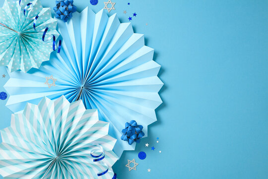 Jewish holiday celebration concept. Greeting card template with blue decorations, paper fans, ribbons, and stars of David confetti. - Powered by Adobe