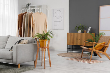 Interior of living room with clothes rack, sofa and armchair