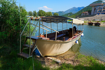 Obraz premium Sightseeing boat moored on the banks of the channel linking Virpazar to the Lake Skadar in Montenegro