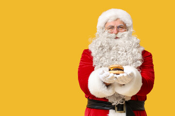 Santa Claus with tasty burger on yellow background