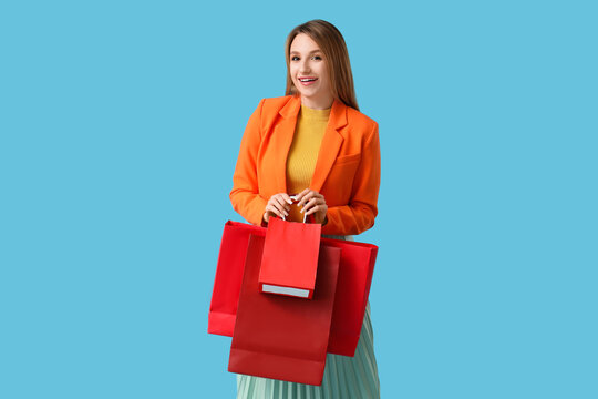 Beautiful young happy woman with shopping bags on blue background