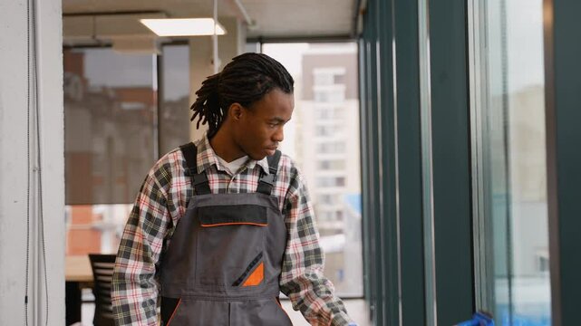 Afro-American janitor cleaning glass windows in office