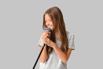 Cute girl with modern microphone on grey background