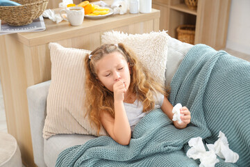 Sick little girl with sore throat and tissue coughing on sofa at home