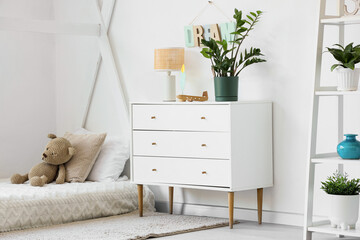 Chest of drawers, cozy bed and toys in light nursery