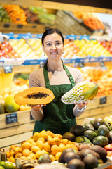 Female grocery store worker offers papaya in grocery department of the supermarket