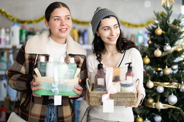 In winter atmosphere, girl friends select and buy present shower cosmetic. Client examine product, make purchase decision and thinking discusses advantages and properties of product.