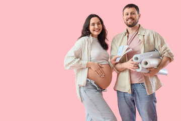 Young pregnant couple with color palettes and wallpapers on pink background. Repair concept