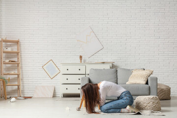 Scared young woman in center of living room during earthquake