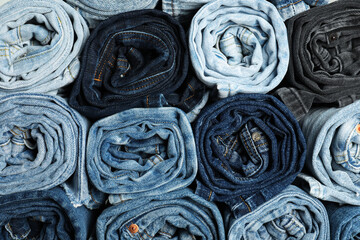 Different stylish rolled jeans as background, top view