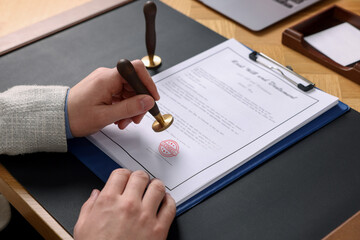 Man stamping document with Licensed stamp at table, closeup