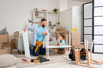 Cute boy with his father assembling shelf unit at home