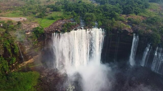 a stunning aerial shot of a massive waterfall plunging from a cliff with dense green vegetation above it Angola