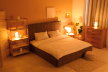 Interior of night bedroom with big bed, shelving unit, commode and glowing lamps near yellow wall