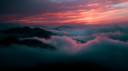 Fototapeta premium Mountains rising above a sea of clouds at sunset.