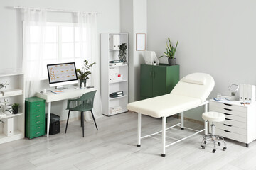 Interior of medical office with doctor's workplace, couch and plants