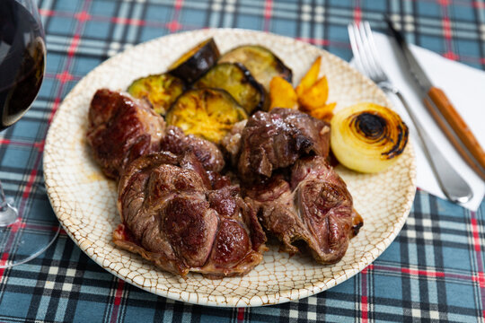 juicy and tender barbecued beef steak garnished with warm fried potatoes, courgettes, onions, complemented by olives and glass of red wine