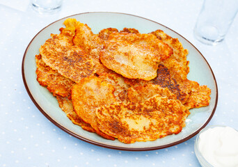 Belarusian potato pancakes draniki with sour cream at plate, nobody