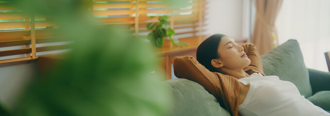 Relaxed young Asian woman enjoying rest on comfortable sofa, calm attractive girl relaxing on...