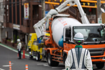 工事車両の停車する道路の交通を整理する交通誘導員