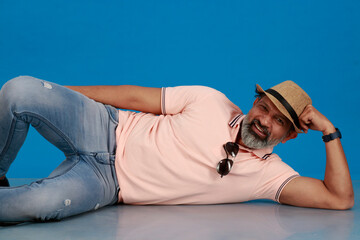 Indian middle age handsome Caucasian man wearing light pink shirt, hat, sunglasses posing against...